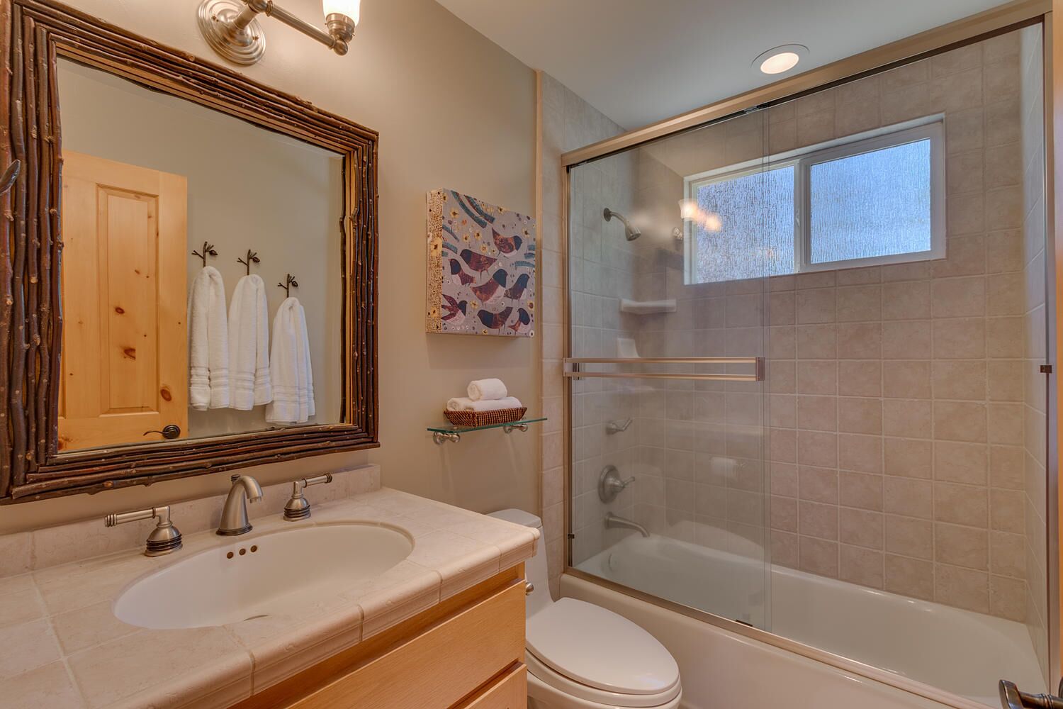 A bathroom with a double sink, a toilet, a glass-enclosed shower, and a large mirror.