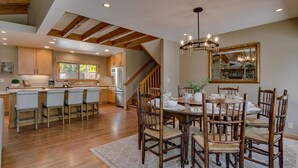 A spacious kitchen with wooden cabinets, a central island with bar stools, and a dining area with a large wooden table and chairs. - Forever Edgewood - Lakeview - TLUXP (Tahoe City)
