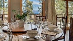 A dining table set for six with a view of trees and mountains through large windows. - Forever Edgewood - Lakeview - TLUXP (Tahoe City)