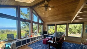 A spacious room with large windows, a ceiling fan, and a view of the outdoors. - One Hundred Thousand Welcomes (Waldport)