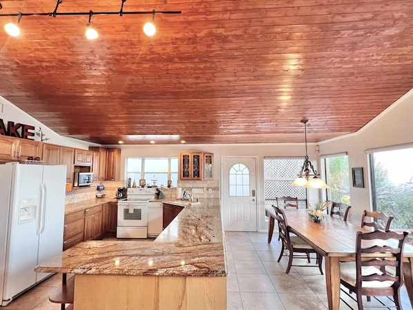 Una cocina con armarios de madera, encimera de granito y comedor con mesa y sillas.