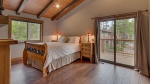 A bedroom with a wooden bed, bedside tables, and a large sliding glass door leading to a deck.