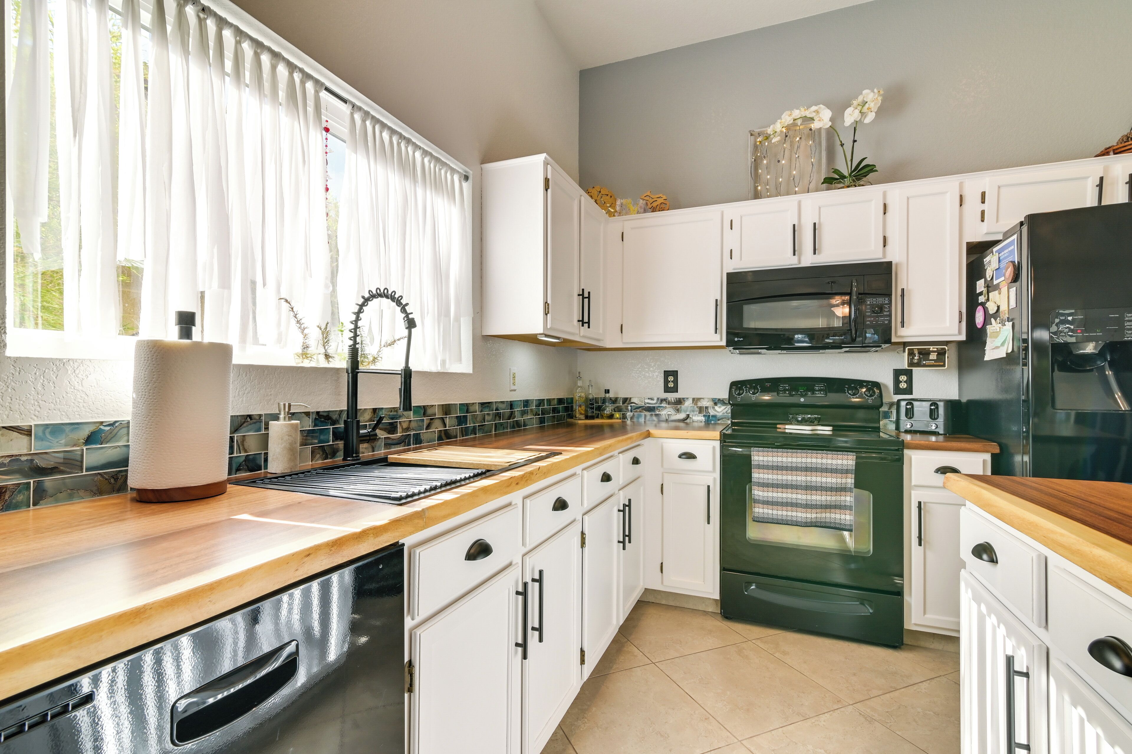 A kitchen with white cabinets, a microwave, a stove, and a refrigerator.