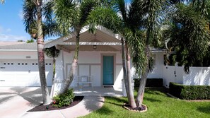 A single-story house with a covered porch, a blue door, and a garage.