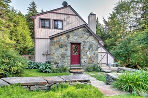 A rustic cabin with a stone facade, a red door, and a small porch. - West Dover Vacation Rental w/ Hot Tub Near Mt Snow (West Dover)