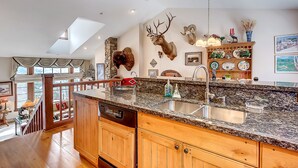 A kitchen with wooden cabinets, granite countertops, a dishwasher, and a large island with a sink.