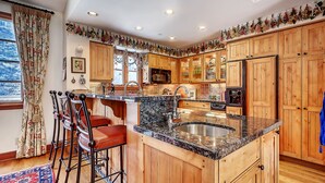 A kitchen with wooden cabinets, a granite countertop, and a bar area with stools.
