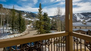 A view from a balcony overlooking a snowy landscape with trees and a clear sky.