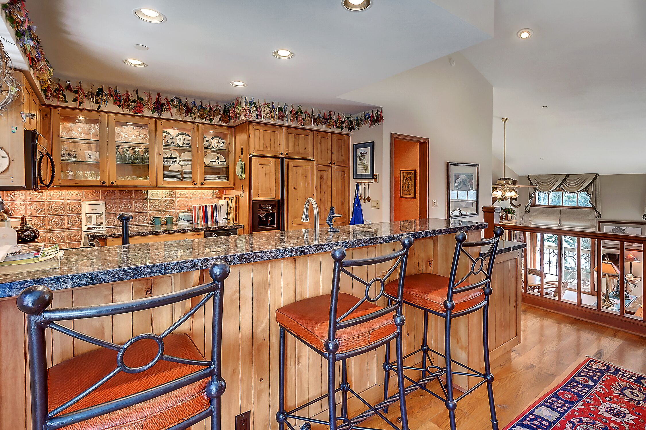A kitchen with wooden cabinets, a granite countertop, and a bar area with stools.