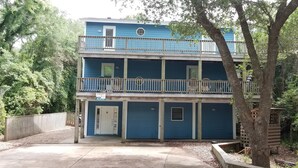 Edificio de dos pisos con fachada azul, un balcón en el nivel superior y una puerta que indica 'RENT'.