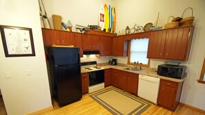 Cocina con gabinetes de madera, refrigerador, estufa, microondas y lavavajillas.