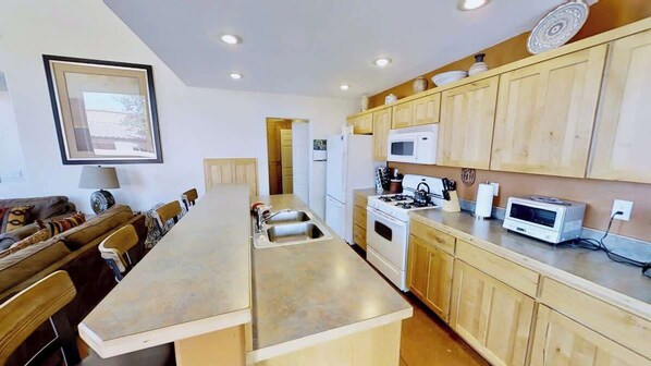 A modern kitchen with wooden cabinets, a central island, and a dining area with a couch and chairs.