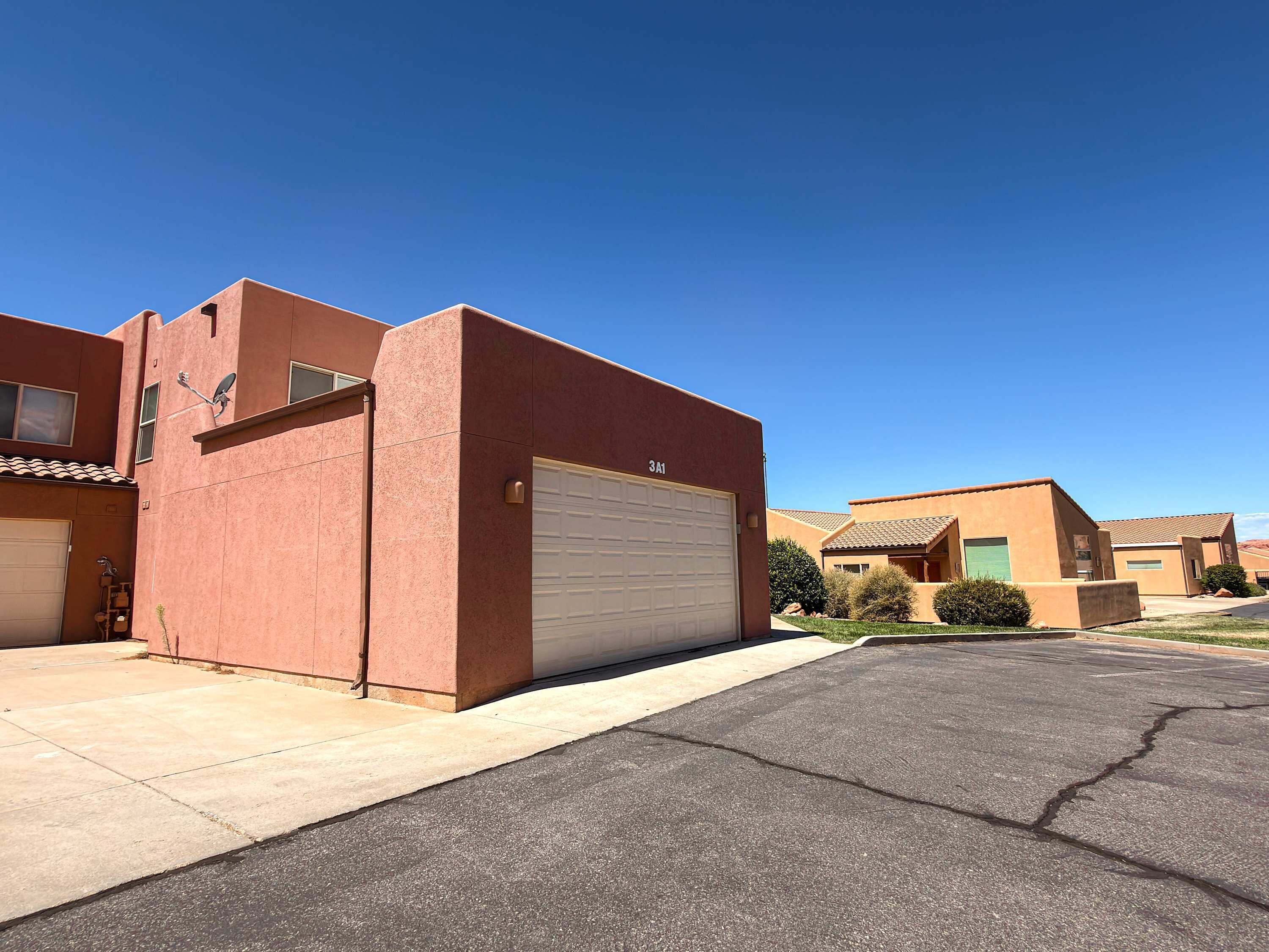 A residential building with a garage, a satellite dish, and a clear blue sky.