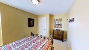 A bedroom with a bed, a dresser, a door, and a mirror on the wall. - Saddle Creek - 3A1, 3 Bedroom 2 and a Half Bath Condo (Moab)