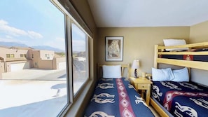 Una habitación con literas, una ventana con vista a edificios y un cuadro en la pared.