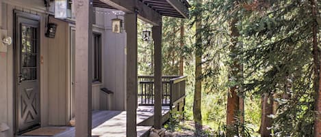 Een houten hut met een veranda, stenen trappen en een bos op de achtergrond.