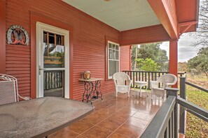 A red building with a porch, a table, and four chairs. - 'August Schmidt' Fredericksburg Cottage w/ Hot Tub (Fredericksburg)