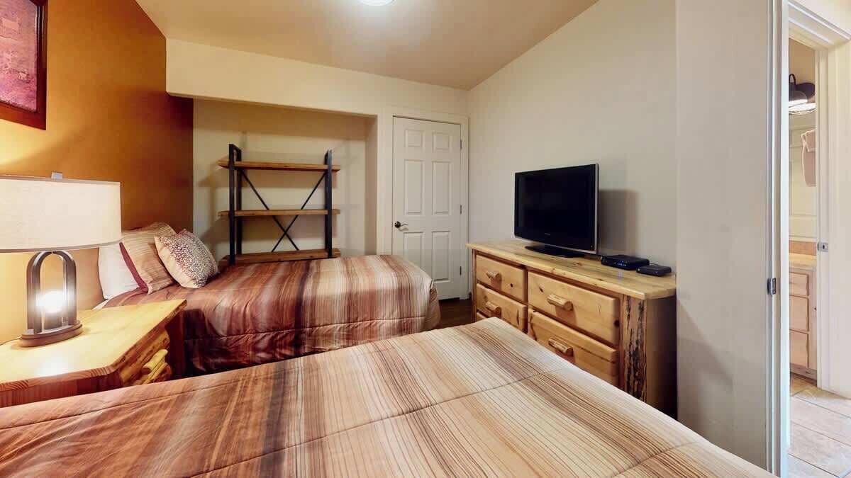 Een slaapkamer met een bed, een televisie, een dressoir en een plank.