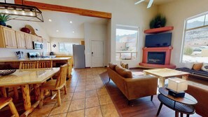 A spacious living area with a fireplace, a dining table with chairs, and a sofa.