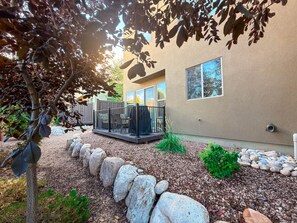 A residential building with a covered patio area, a stone pathway, and a tree with dense foliage.