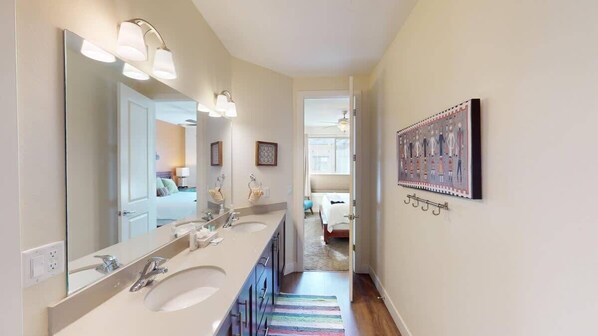 A bathroom with a large mirror, two sinks, and a colorful striped rug.