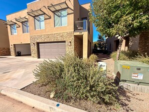 A residential building with a garage, a balcony, and a green utility box. - Entrada at Moab - 640-Beautiful Condo Downtown Moab (Moab)
