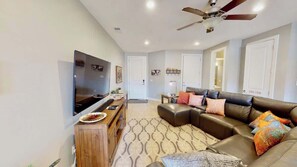 A modern living room with a flat-screen TV, leather sofa, patterned rug, and a ceiling fan. - Entrada at Moab - 668, Wolf Den (Moab)