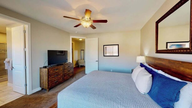 A hotel room with a bed, a ceiling fan, a dresser, a television, and a door leading to another room. - Entrada at Moab - 668, Wolf Den (Moab)
