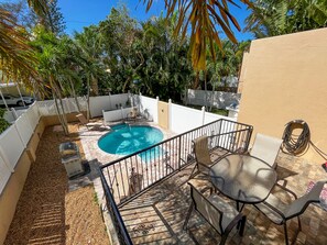 A backyard with a swimming pool, patio furniture, and a white fence. - Walk to the Beach & Village, Heated Pool Oasis, Spacious (Sarasota)