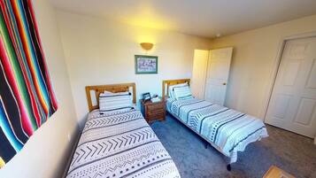 Une chambre avec deux lits simples, une table de chevet avec une lampe et une porte.