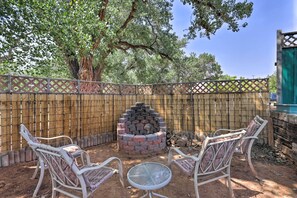 An outdoor patio with a brick fire pit, two wicker chairs, and a glass table. - 'Rustic Retreat' Moab Townhome w/ Grill & Fire Pit (Moab)