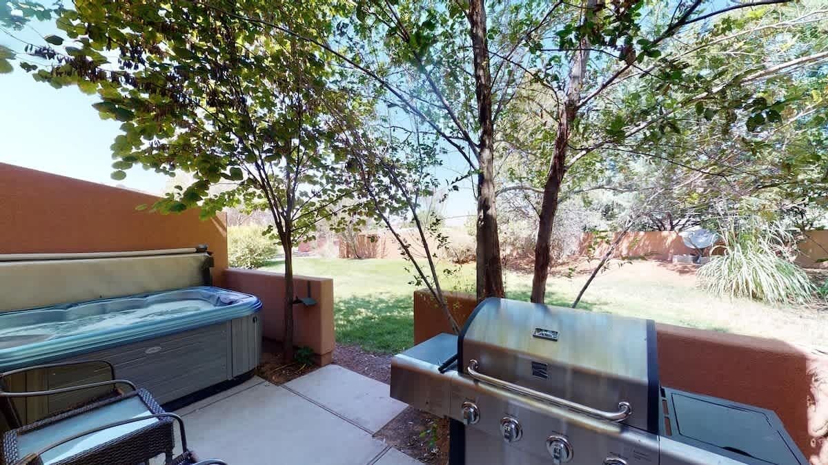 An outdoor patio with a hot tub, grill, and seating area.