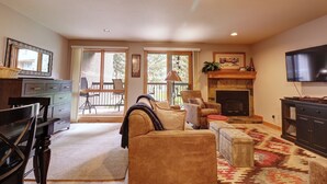 A living room with a fireplace, a television, and a dining area with a table and chairs. - Beautiful Ski in/out Condo, Great Location! CM244 (Copper Mountain)