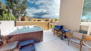 A patio with a hot tub, a grill, and outdoor seating.
