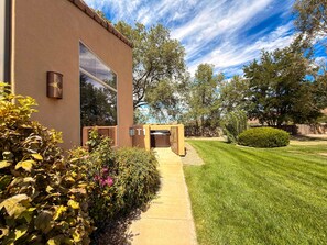 A building with a large window, a pathway leading to the entrance, and a well-maintained lawn.