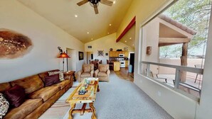 A spacious living room with a high ceiling, a wooden coffee table, a sofa, and a dining area with a table and chairs. - Return to the Old West - T1, Private Hot Tub With (Moab)