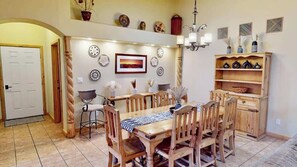 A dining area with a wooden table and chairs, a chandelier, and decorative plates on the wall. - Arches West - 393, Townhome In Moab's most request (Moab)
