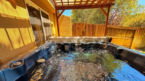 Un jacuzzi con una terraza de madera y una valla de madera al fondo.