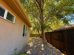 A residential backyard with a house, a wooden fence, and a tree.
