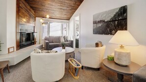A modern living room with a fireplace, white furniture, and a large window. - Ski In/Out Right By The Lift with Slope side Hot Tub FP304 (Copper Mountain)