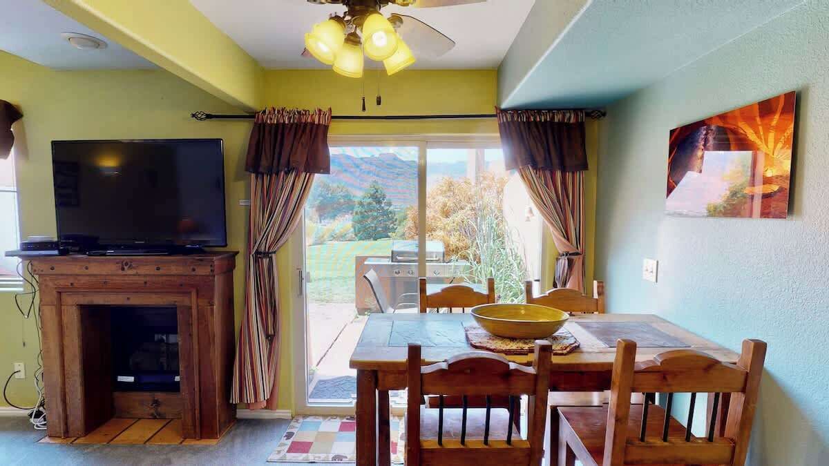 Een eethoek met een tafel, stoelen, een televisie en een open haard.