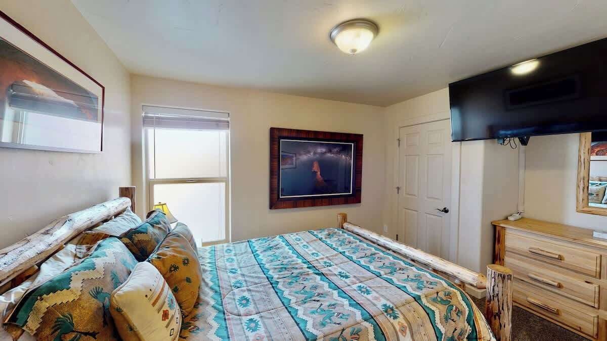 Une chambre à coucher avec un lit, une commode, un téléviseur et une fenêtre.