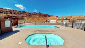 A pool area with a safety sign, a fenced pool, and a building in the background. - Vista Villa - 3A5, Spacious Condo With Panoramic P (Moab)