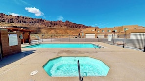 A pool area with a safety sign, a fenced pool, and a building in the background.