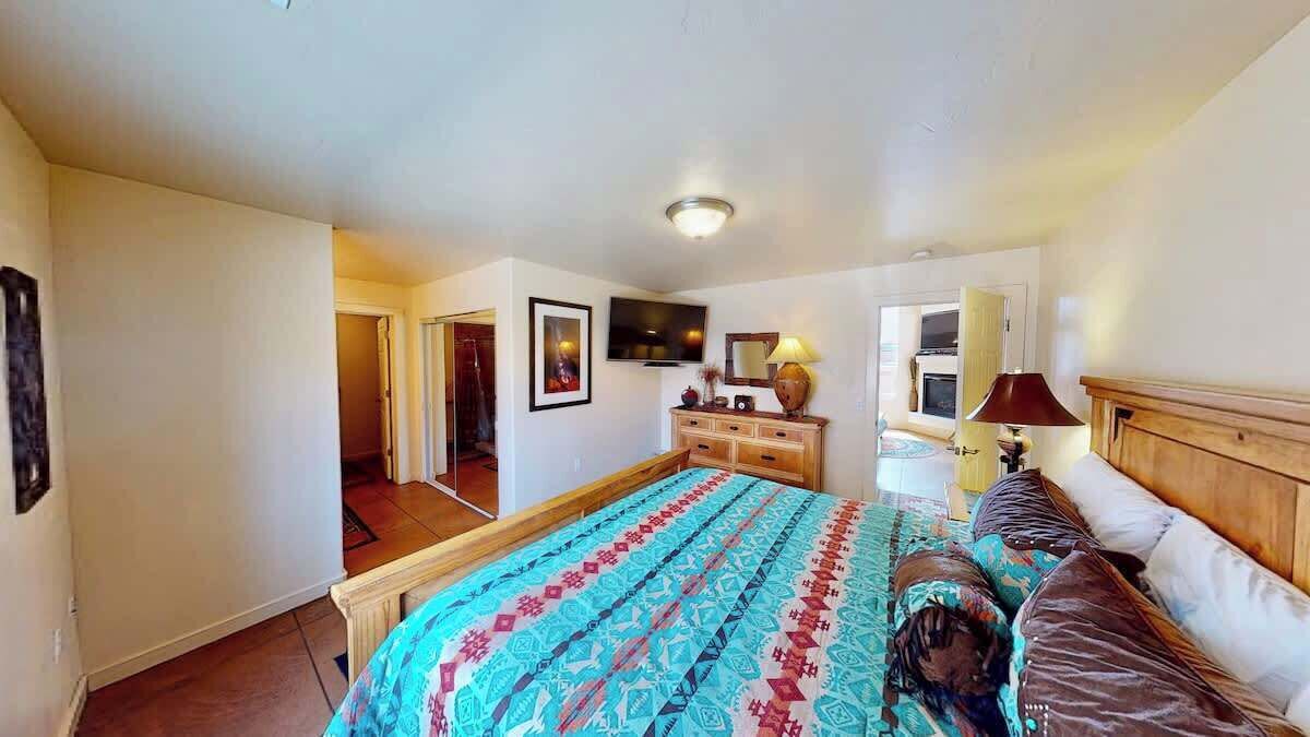 A bedroom with a bed, dresser, television, and a door leading to another room.