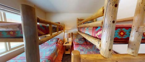 Een kamer met stapelbedden, een tafeltje en een lamp.