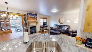 A modern living room with a fireplace, a sofa, and a dining area with a table. - The Rock - 3461 (Moab)