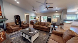 A spacious living room with leather sofas, a coffee table, and ceiling fans.