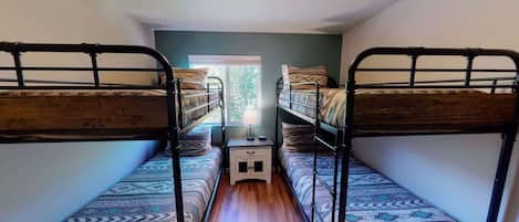 Una habitación con literas, una mesita de noche pequeña y una ventana.