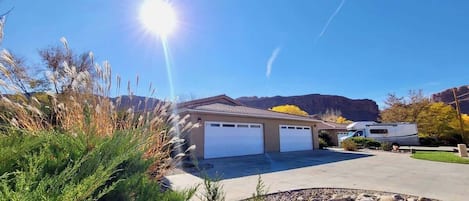 A residential property with a garage, a driveway, and a vehicle parked in the background.